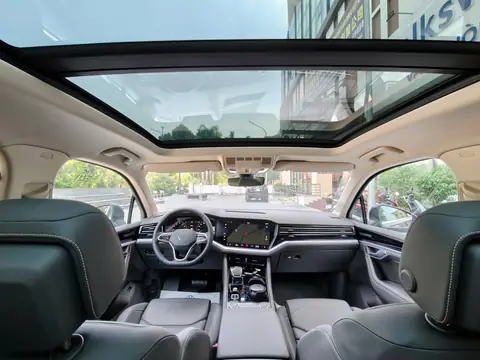 A bright SUV cabin under a wide panoramic glass panel, the windshield ahead